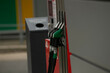 © Alena - Fuel pump nozzles at urban station green and black hoses resting on metal dispenser beside trash bin, concrete forecourt and payment terminal, city
