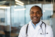 © Liubomir - Mature african american male doctor in lab coat with stethoscope, smiling confidently for a professional portrait that conveys expertise, trust and compassionate patient care in clinic