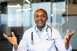 © Liubomir - Smiling african american male doctor in white coat and stethoscope speaking to camera during a telemedicine video call, offering medical advice, support and virtual consultation