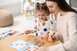 © New Africa - Mother and her daughter playing with toys at wooden table indoors