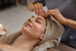 © New Africa - Beautiful woman wrapped in towel receiving facial massage on couch indoors, closeup