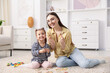 © New Africa - Mother and her daughter playing with toys on floor at home