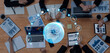 © InfiniteFlow - A diverse team of professionals collaborates around a wooden table, utilizing laptops and tablets to analyze data and strategy, inspiring innovation and productivity. Trope