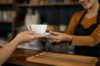 © apichat - Barista serving coffee to customer in cafe