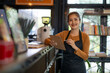 © apichat - Asian female barista smiling and holding clipboard in cafe