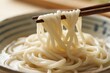 © zhang yongxin - Close-up of udon noodles being lifted with chopsticks from a bowl