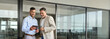 © insta_photos - Two happy busy professional business men executive business team working together standing in office holding tab using digital tablet computer tech managing data standing in corporate office.
