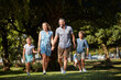© peopleimages.com - Happy family, parents and holding hands with kids outdoor for care, laugh and support on holiday. Father, mother and children at park with connection, funny and walk together on vacation for travel