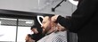 © volha_r - Professional barber concentrating while skillfully using clippers to cut and style a male customer's hair in a modern barbershop, creating a trendy and polished look