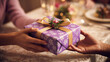 © Eatherpixels - Hands exchanging a beautifully wrapped purple gift box at a festive celebration