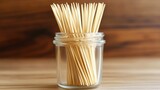 Many Pointed Bamboo Toothpicks Arranged in a Clear Glass Container on a Wooden Surface