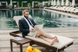 © dsheremeta - Businessman working on laptop by the poolside