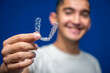 © Manuel - Young man holding a clear removable aligner, showing modern orthodontic treatment for teeth straightening and dental health