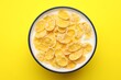 © New Africa - Tasty corn flakes with milk in bowl on yellow table, top view