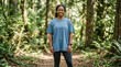 © Iryna - A woman stands on a dirt trail surrounded by trees in a forest. She is wearing a blue t-shirt for mockup.