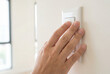 © Meow Creations - Hand of a young person reaching out to press a white wall light switch button