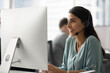 © fizkes - Smiling Brazilian woman call center worker technical support agent in wireless headset talking to client via video call guiding conversation providing remote consultation using pc at office workplace