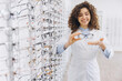 © anatoliycherkas - Optometrist presenting new eyeglasses frames in an optical store, assisting customer with vision correction