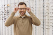 © anatoliycherkas - Happy man trying on new eyeglasses in an optical shop, choosing vision correction frames for better sight