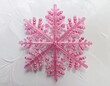 © Riko - A pink plastic snowflake on white background