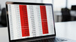 © QQPK14 - A laptop screen displays a spreadsheet with numerical data and percentages, featuring red highlights indicating specific values, likely related to financial or business analysis