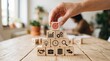 © Laiba - Pyramid of wooden blocks with target, chart, gear, lightbulb, clock, magnifier, handshake, suitcase, database, and arrows icons on a desk