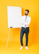 © luismolinero - Full-length shot of businessman giving a presentation on white board over isolated yellow background with confuse face expression