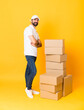 © luismolinero - Full-length shot of delivery man among boxes over isolated yellow background with arms crossed and looking forward