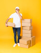 © luismolinero - Full-length shot of delivery man among boxes over isolated yellow background covering mouth with hands