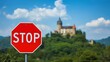 © LimeSky - Scarlet stop sign before a hazy castle in Slovenská Ľupča, Slovakia. Traffic marker with an ancient structure on a hill and wooded backdrop