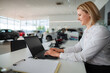 © Jelena - Woman sales manager working on laptop in car dealership