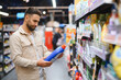 © Serhii - Man shopping for household detergent in supermarket aisle