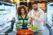 © Serhii - Couple shopping groceries comparing list in supermarket