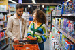 © Serhii - Couple shopping for cleaning supplies in supermarket aisle
