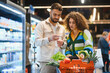 © Serhii - Couple checking shopping list buying groceries in supermarket
