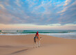 © muratart - A woman in a red turban riding a camel across the thin sand dunes of the in Western Sahara Desert with Atlantic ocean meets in the background - Morocco, Africa