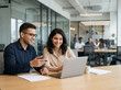 © Someone Cooked Here - young indian professionals working together at laptop in modern corporate office teamwork collaboration concept with copy space