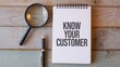 © ART BY SAIFUL - Vibrant photo of Notepad with the text Know Your Customer with a pen and magnifying glass on a wooden surface