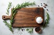 © miss irine - Rustic wooden cutting board with fresh rosemary sprigs, coarse sea salt, black peppercorns. Overhead view of culinary ingredients arranged for food preparation on textured surface, ready for recipe