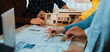 © InfiniteFlow - A diverse team engages in brainstorming and planning an architectural project. The scene showcases hands working on models and drawings in a creative workspace environment. SACTR