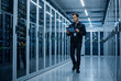 © Anim - IT specialist walking with tablet in modern data center aisle near servers