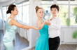 © JackF - Focused female dance teacher attentively fine-tuning positions of teenage students during dance class to improve partner ballroom dancing technique ..