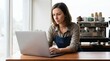 © Dialova Creative - Focused woman entrepreneur diligently managing her small business online from a modern cafe, leveraging digital tools for efficient operations and growth