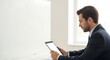 © Adi - Young businessman in a suit holding a tablet computer and looking at its screen in an office