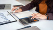 © Fahng - Close up hand of Businesswoman using a calculator to calculate the company's financial performance and budget. concept of auditing.