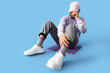 © Pixel-Shot - Man in cap with stylish sneakers sitting on blue background