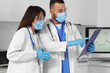 © Pixel-Shot - Young doctors with clipboard analyzing scientific data in laboratory