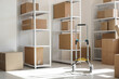 © Pixel-Shot - Interior of light warehouse with hand truck and cardboard boxes on shelving units