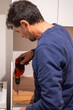 © Nanci - Man using power tool drilling into a wooden surface, performing diy home renovation, maintenance, and assembling furniture, showing productivity and handyman skills