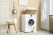 © Pixel-Shot - Stylish laundry room with modern washing machine, wicker basket and bottles of detergent